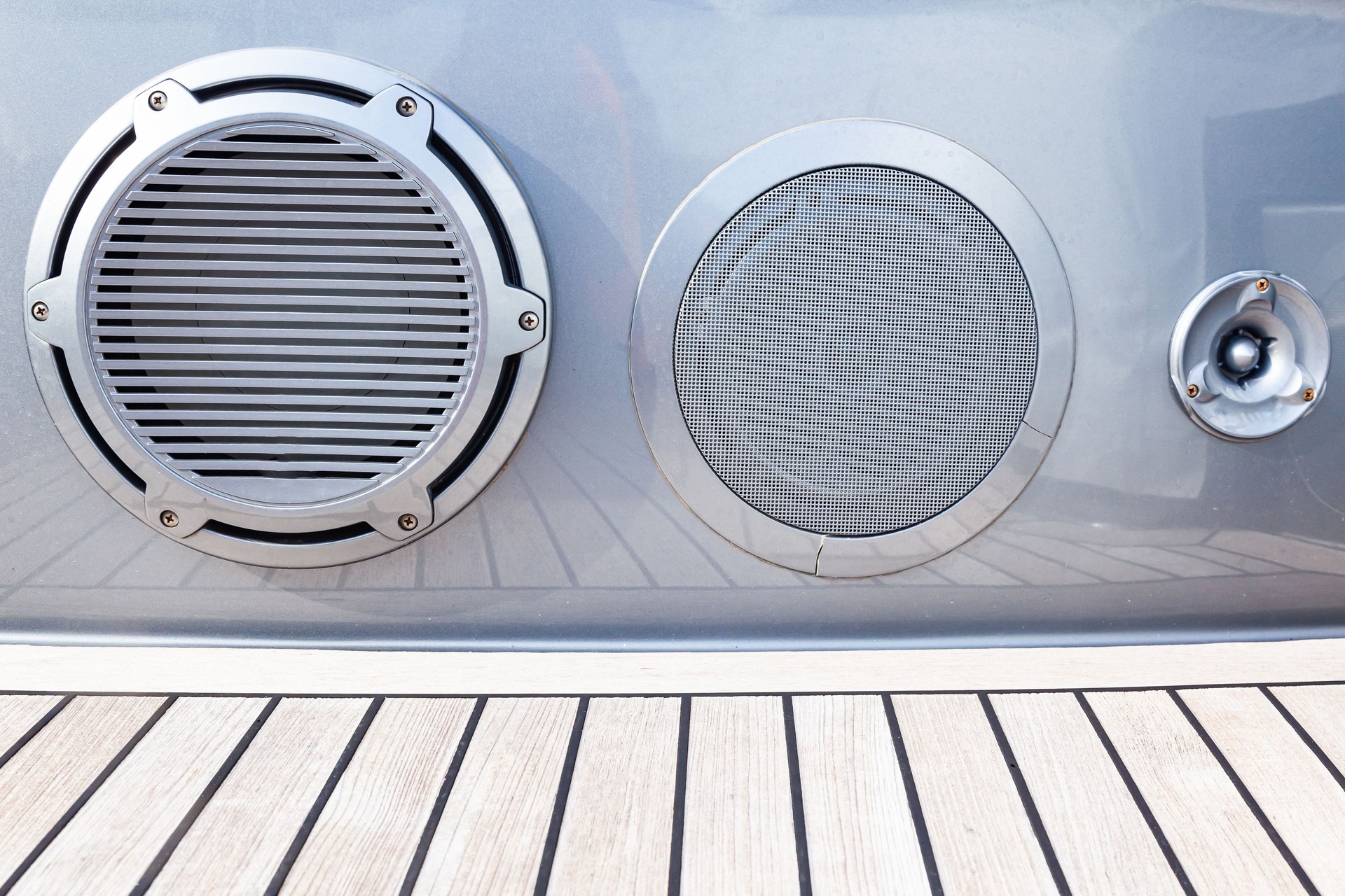 Several music speakers are integrated into the luxury yacht hull. Music speaker integrated into the sofa body on the teak deck of a luxury yacht.