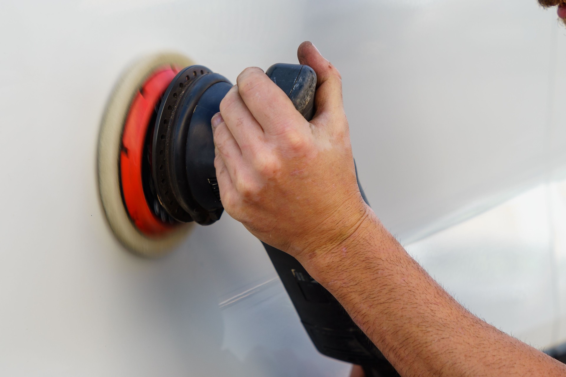 Detail of the hand with the polisher, polishing the car door.